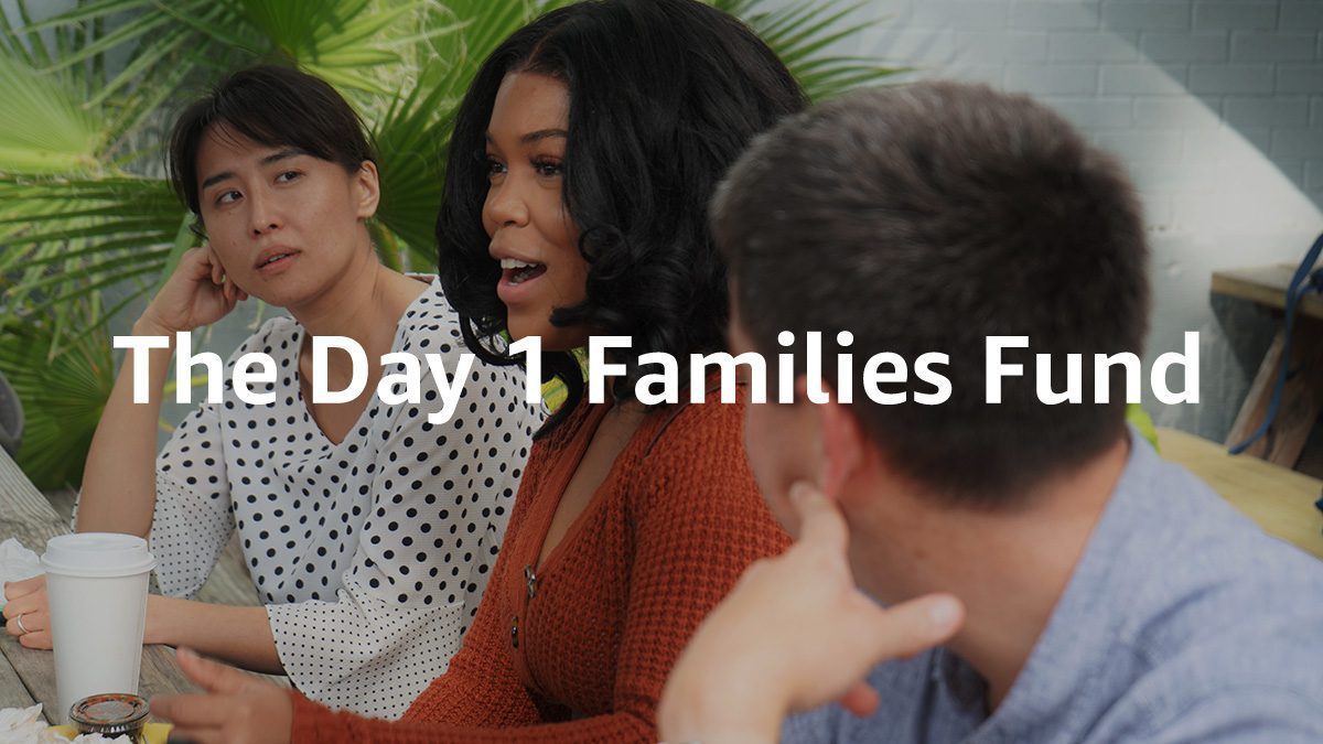 Medium shot of ECHO staff talking at table with text on top that says "The Day 1 Families Fund"