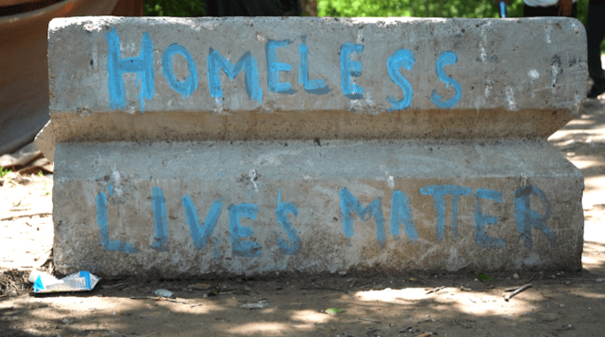 Concrete block on dirt path painted with words "Homeless lives matter"