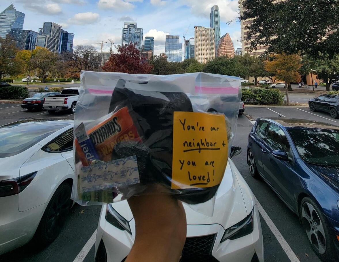 Photo of hand holding care kit in front of Austin skyline